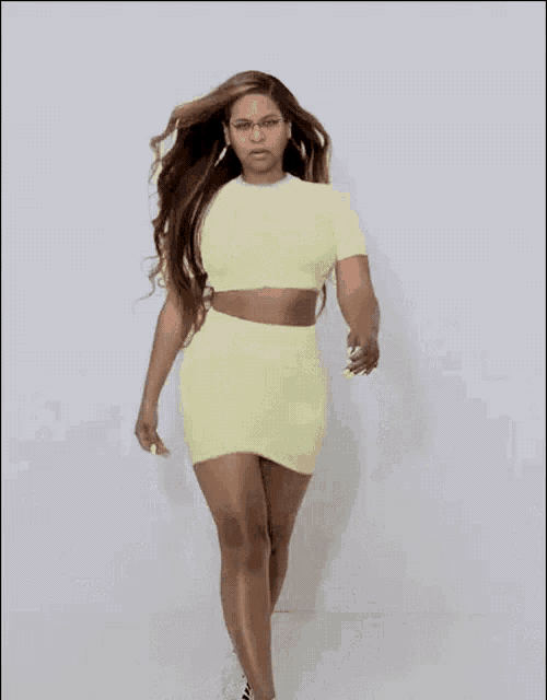 a woman in a yellow crop top and skirt