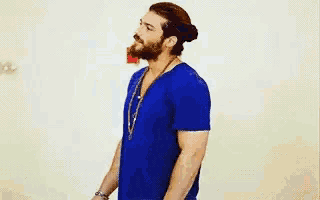 a man with a beard is wearing a blue shirt and necklace .