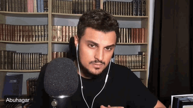 a man wearing headphones stands in front of a microphone with the name abuhagar on the bottom