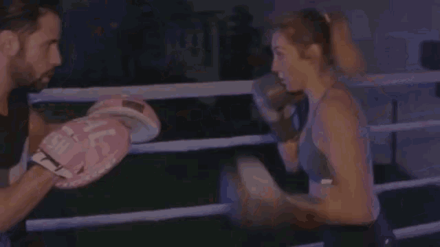 a woman and a man are boxing in a ring .