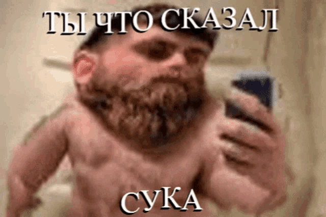 a shirtless man with a beard is taking a selfie with a foreign language caption