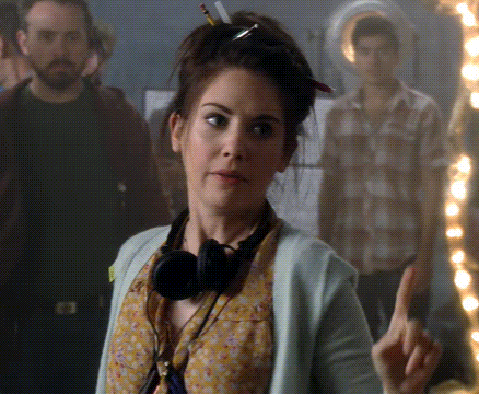 a woman wearing headphones and a sweater is pointing her finger