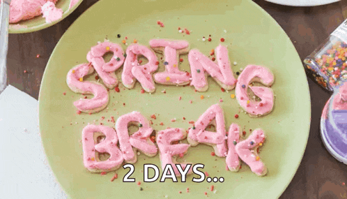 a green plate topped with pink frosted cookies that spell out spring break