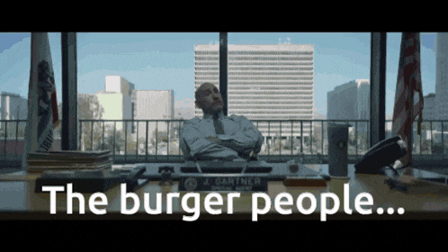 a man sits at a desk with the words " the burger people " written on it