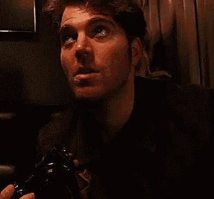 a man is holding a camera in his hand and making a funny face