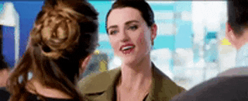 a woman in a green jacket is talking to another woman in a crowded room .