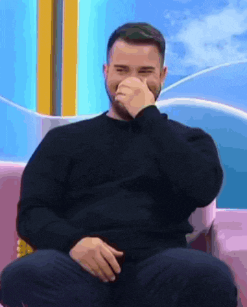 a man wearing a black sweater is covering his nose with his hand