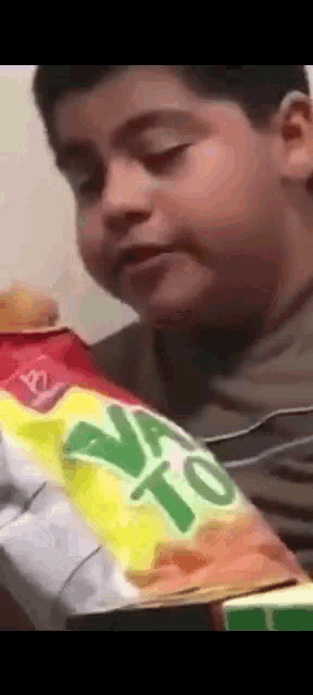 a young boy is looking at a bag of tortilla chips .