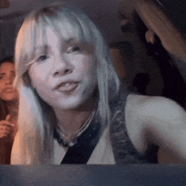 a woman with blonde hair is sitting in a car looking out the window