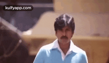 a man with a mustache is wearing a blue shirt and a white shirt .