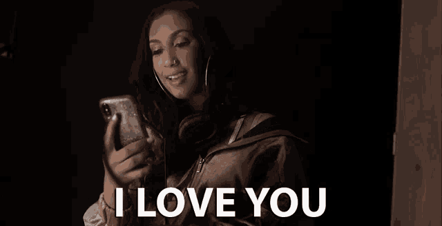 a woman is taking a picture of herself with her phone and saying `` i love you '' .
