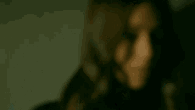 a blurry picture of a woman 's face with her eyes closed .