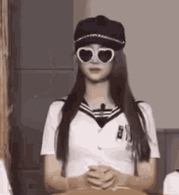 a woman wearing a hat and heart shaped sunglasses .