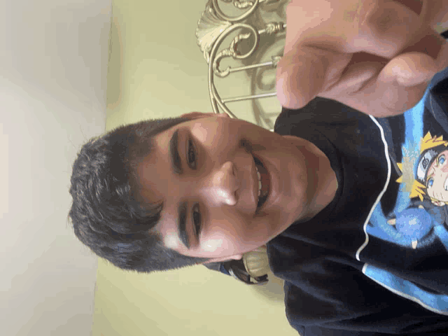 a young boy wearing a black shirt with naruto on it smiles