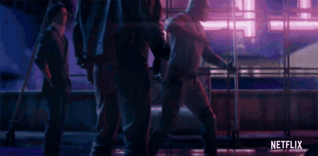 a group of men are standing in a dark room with a netflix logo in the corner .