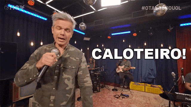 a man singing into a microphone with the word caloteiro on the screen behind him
