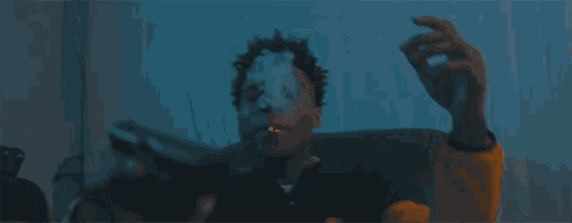 a man is sitting on a couch smoking a cigarette and holding a knife .