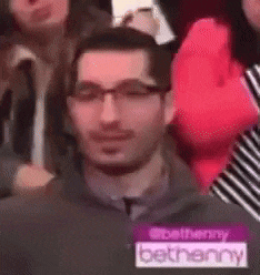 a man wearing glasses and a name tag that says bethanny is standing in a crowd .