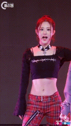 a woman in a black crop top and red plaid pants is smiling and waving