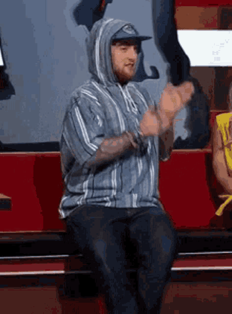 a man in a hoodie is sitting on a bench .