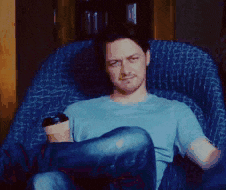 a man in a blue shirt is sitting in a chair holding a cup