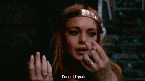 a woman wearing a headband and a ring is smoking a cigarette and says i 'm not oprah .