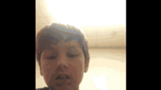 a young boy with his eyes closed is looking at the camera