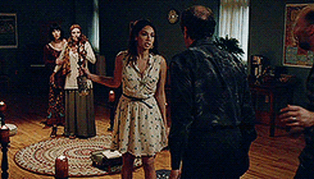 a group of people are standing in a living room with candles on the floor .