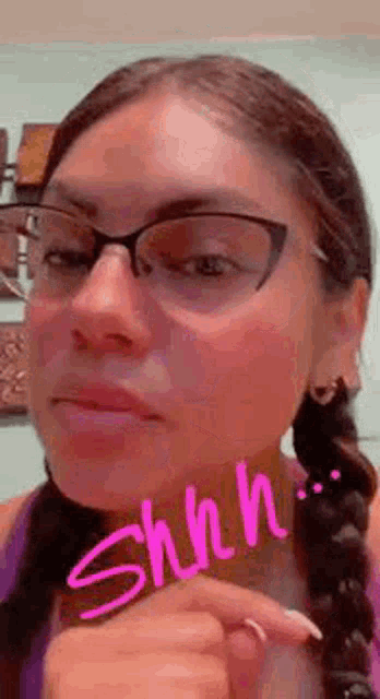 a close up of a woman wearing glasses and a braided hair .