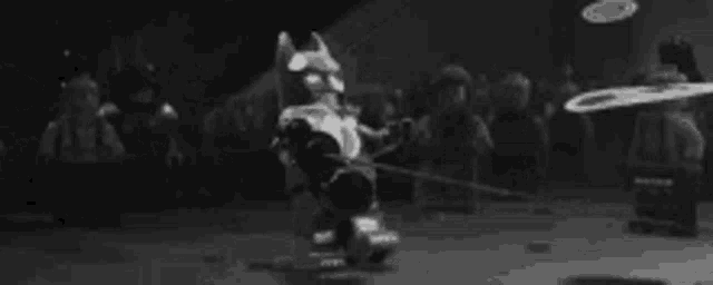 a black and white photo of a cartoon character holding a sword in a crowd .
