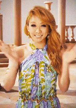 a woman in a floral dress is smiling with her hands in the air