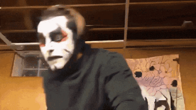 a man with a mask on his face is standing in front of a wall with a drawing of a cat