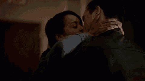 a man and a woman are kissing in a dark room in a room .