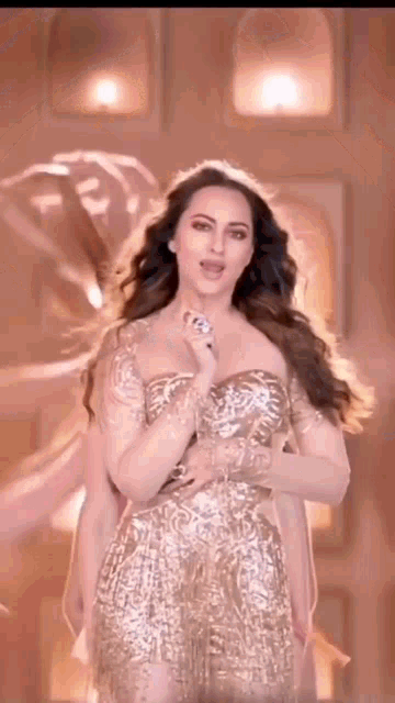 a woman in a gold dress is singing into a microphone while standing in front of a building .