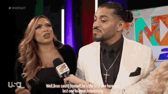 a man in a suit and tie is talking to a woman in front of a microphone ..