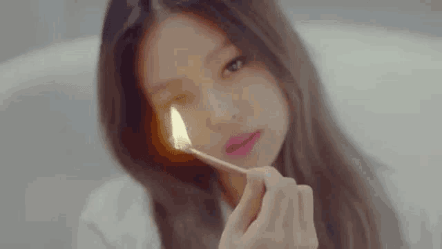 a close up of a woman holding a lit match in front of her face .