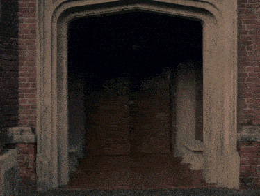 a man is standing in a doorway with a brick wall behind him
