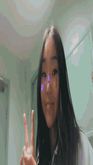 a girl with purple butterflies on her face is taking a selfie .