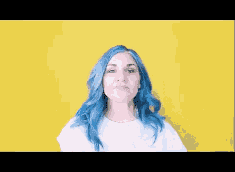 a woman with blue hair is wearing a white shirt and making a face