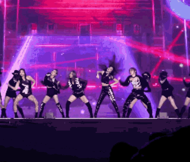 a group of women are dancing on a stage in front of a red light