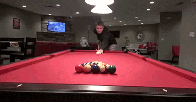 a man is playing pool in a room with a clock on the wall that says 3:00