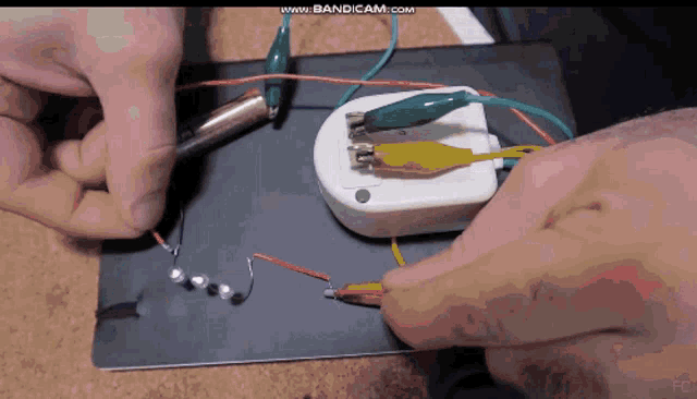 a person is working on a circuit board with the website www.bandicam.com visible