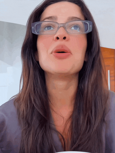 a woman wearing glasses looks up at the camera