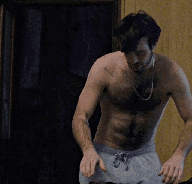 a shirtless man with a tattoo on his arm is standing in front of a door