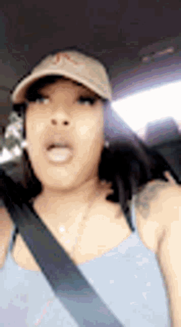 a woman is wearing a hat and a seat belt while driving a car .