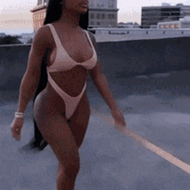 a woman in a bikini is walking on a street