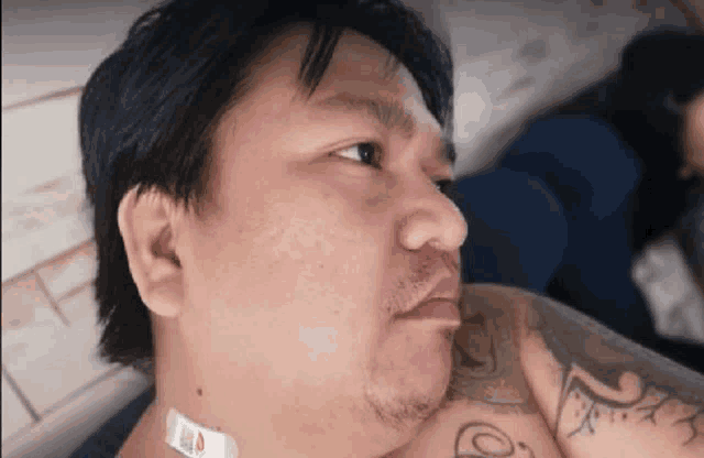 a man with a tattoo on his arm is laying on a bed with a bandage around his neck .