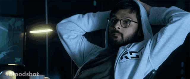 a man wearing glasses and a hoodie with the letters gs on the front