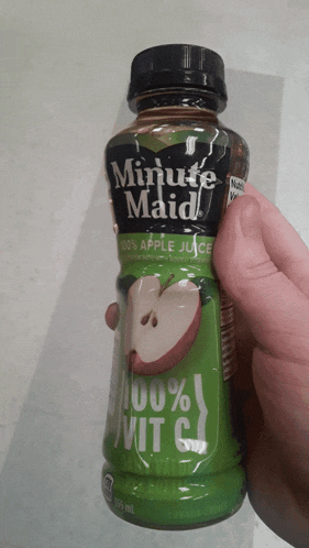 a hand holding a bottle of minute maid 100 % apple juice