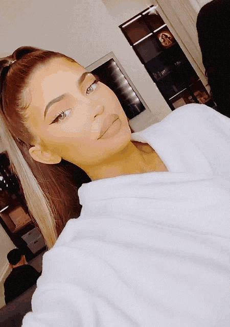 a woman taking a selfie with a white robe on